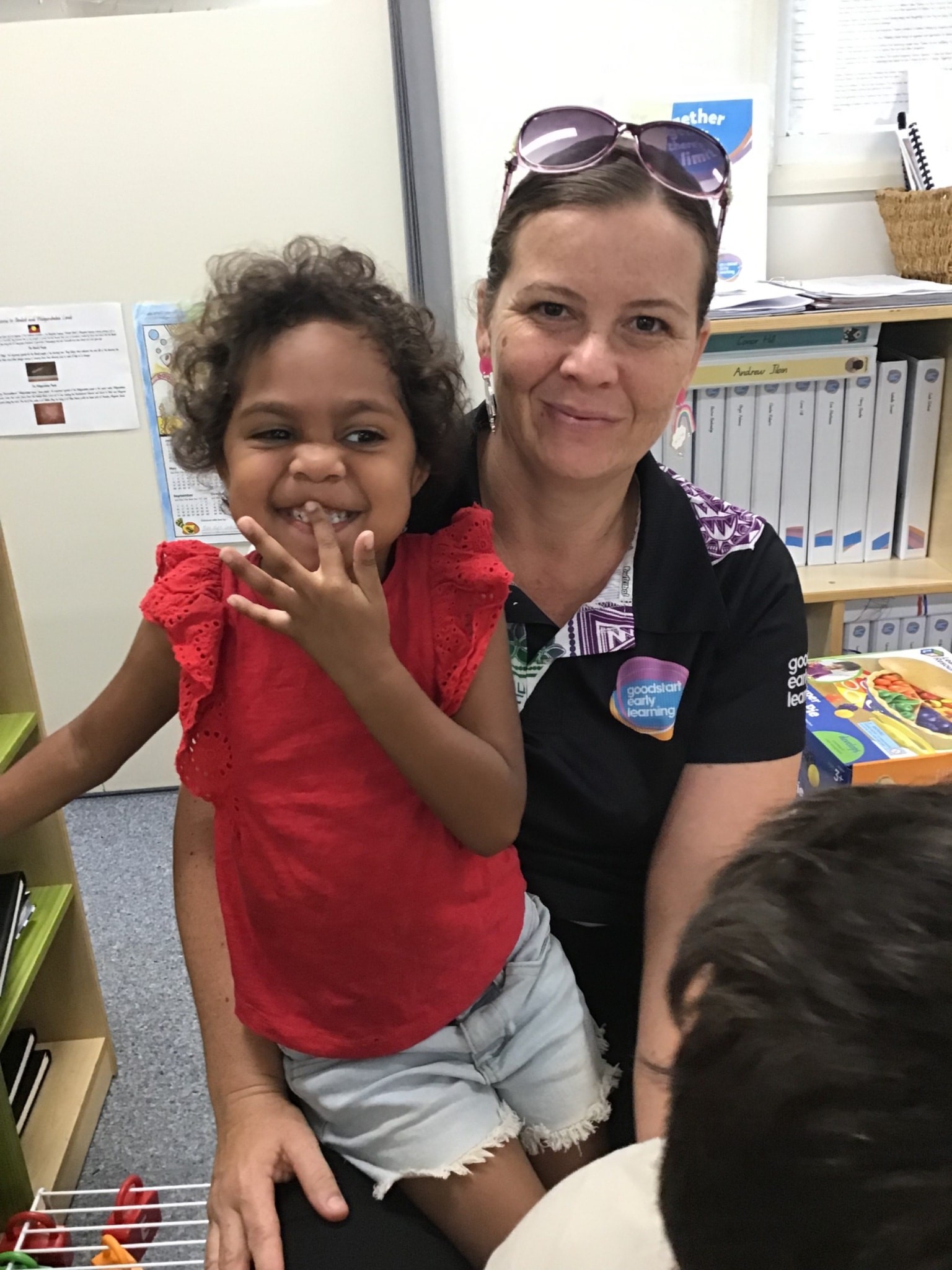 Kylie sitting with a student, smiling happily.