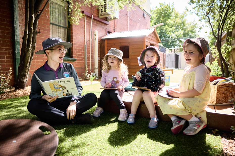 A teacher sits and reads with three students